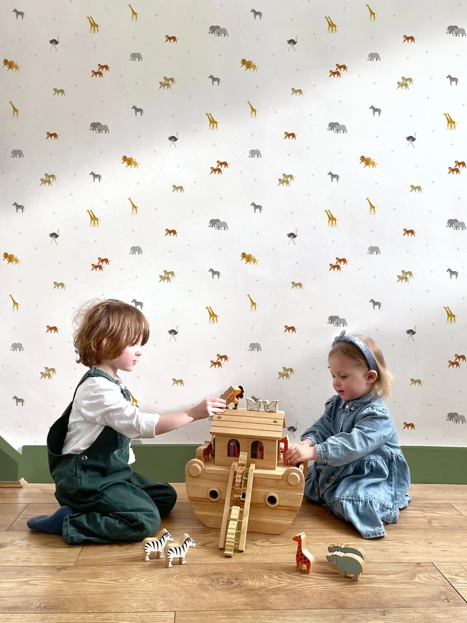 Children playing with wooden Noahs Ark with Ducks In A Row Star Safari Wallpaper behind them
