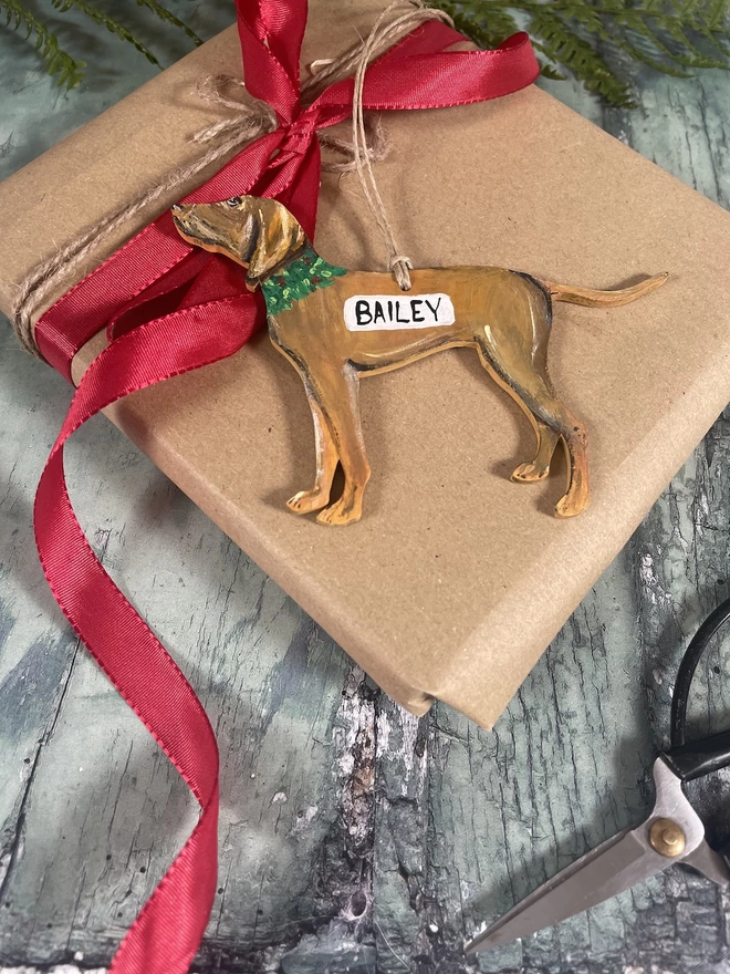 A Hungarian Vizsla Christmas decoration placed on a wrapped gift