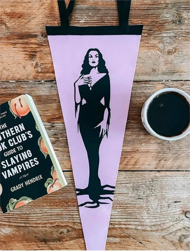 a lilac and black felt pennant for the wall, printed with the image of Vampira