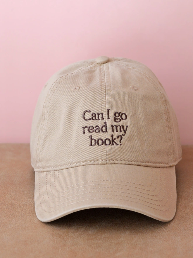 'Can I Go Read My Book?' Cotton Baseball Cap beige on a table