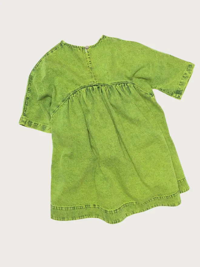Back flat lay of the Studio Koter Rumi dress in green acid-wash denim, showing the button keyhole closure and gathered skirt.