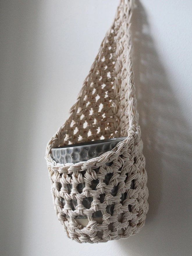 cream ivory indoor hanging wall planter plant basket handmade porch decor crochet boho eco friendly natural plant styling, indoor small ecru jute hanging wall planter, cream fabric wall mounted plant holder, handmade crochet plant basket, handmade sustainable crochet decor, rustic natural organic homeware accessories, ivory hanging plant holder