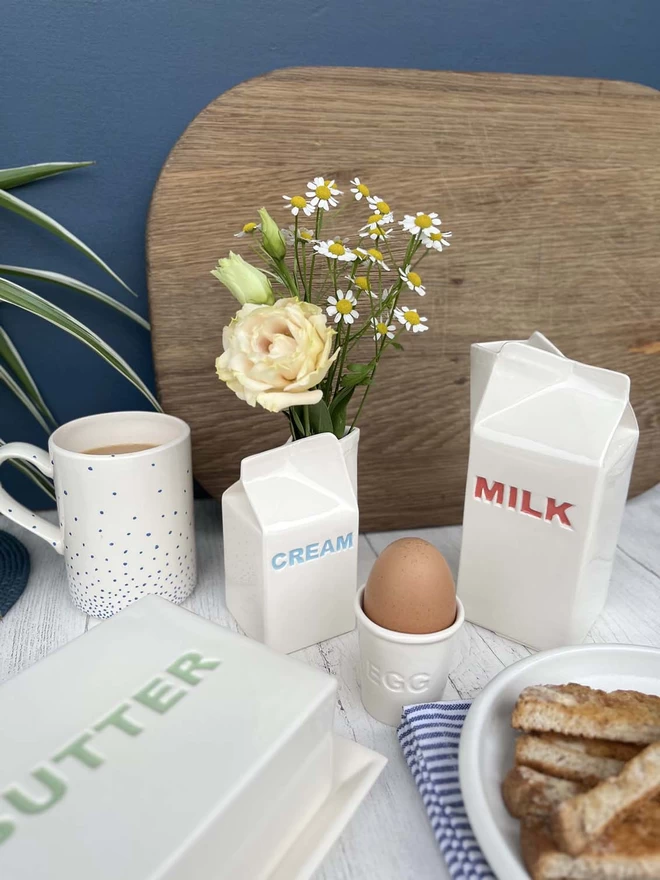 A small handmade ceramic carton is looking beautiful being used as a flower vase.