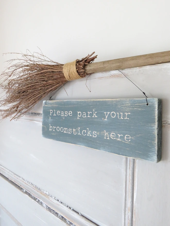 Distressed hand painted wooden sign with broomsticks message