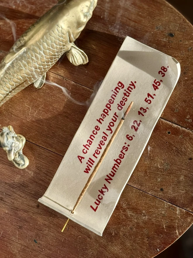 Fortune Incense Holder, an incense holder sitting on a wooden surface. It is joined by a fish sculpture. 