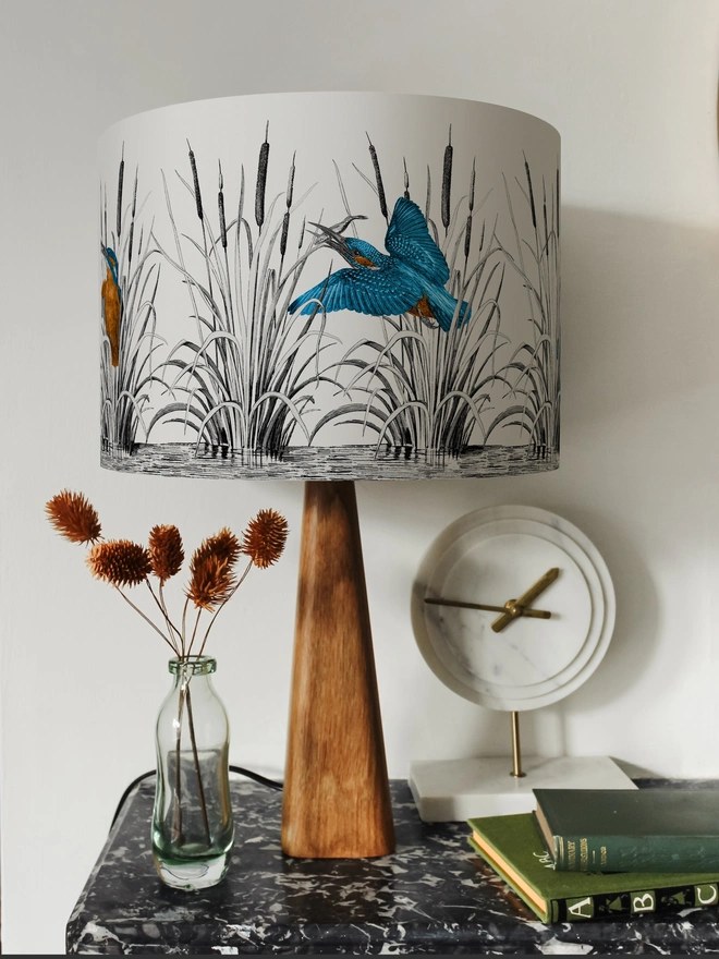Handmade lampshade featuring vibrant kingfishers among bulrushes in a whimsical countryside-inspired design, combining nature, colour, and artisan style.