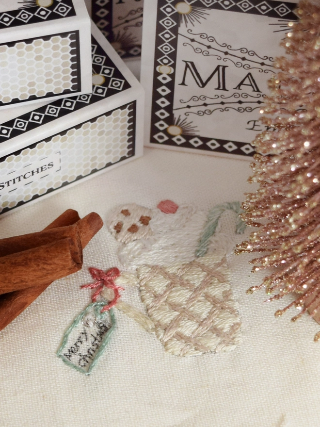 A knit style Mug filled with Cocoa, whipped cream a candy cane and cookie.  Shown with sticks of cinnamon and tinsel.