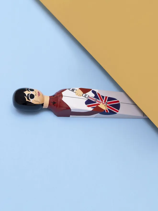 Wooden Door Stopper (Our Noel), a colourful wooden door stop sitting under a door.