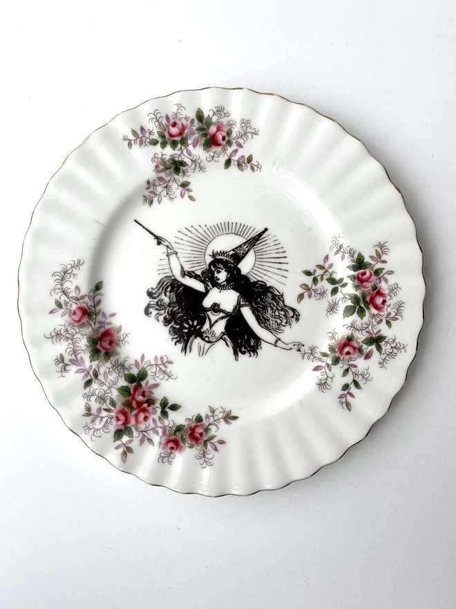 vintage plate with an ornate border, with a printed vintage illustration of a witch waving her wand in the middle 