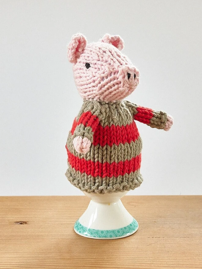 Egg Cosy Pigs Table Decoration (Set Of 2), a colourful pig cosy sitting on a wooden surface. 