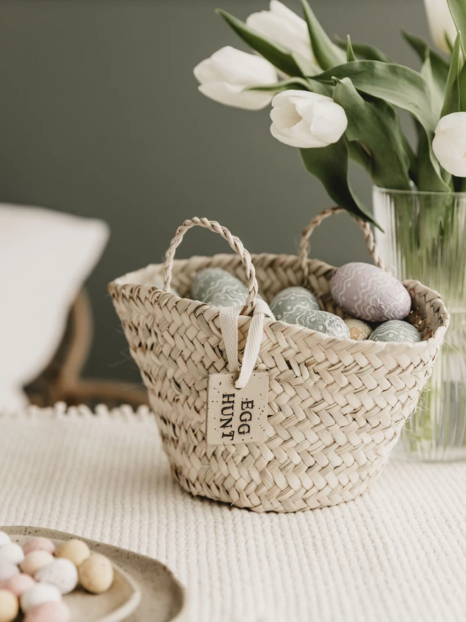 wicker basket filled with fabric eggs and tied with an egg hunt tag