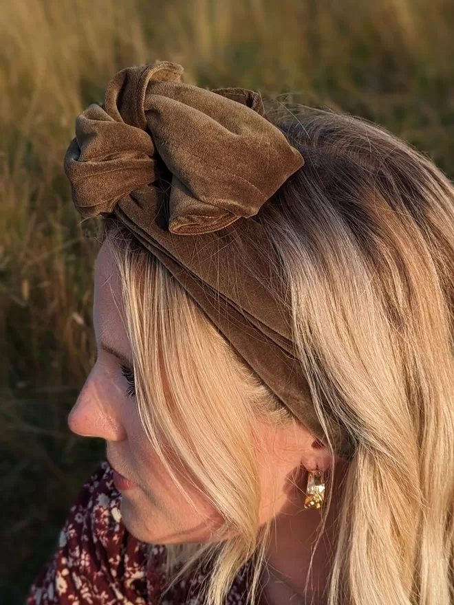 A caper green velvet fabric wrap-style headband on a blonde woman with her hair down.