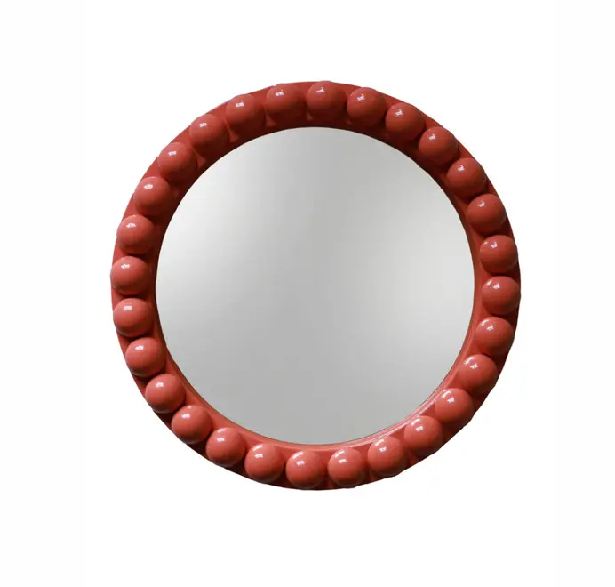 Round oversized bobbin mirror with a decorative bobbin-style wooden frame, hanging on a white wall.