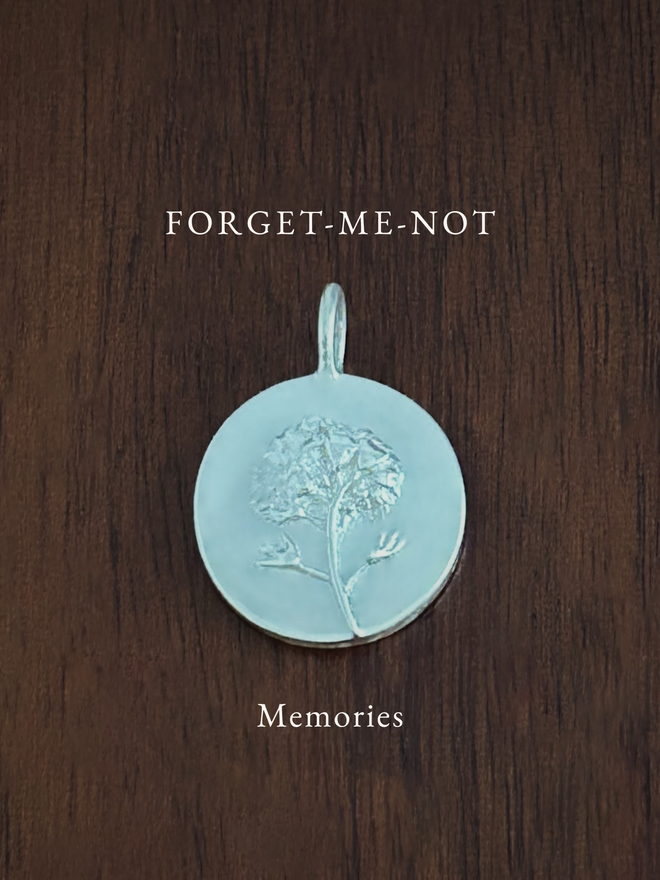 Sterling Silver Forget-Me-Not Coin Charm on a dark background with the language of flowers meaning, memories