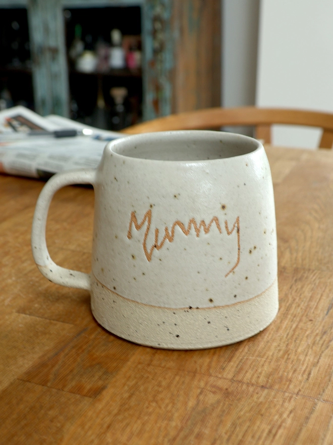 Personalised Kids' Handwriting Handmade Stoneware Mug on table with 'mummy' 