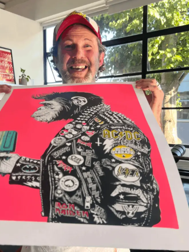 A side profile print of a metal monkey wearing a  punk leather jacket decorated with music band patches, holding an icecream against a neon pink background. 