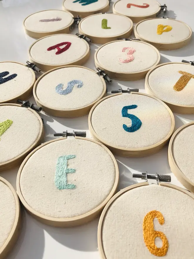 custom letter or number embroidered hoop. selection of cotton hoops embroidered with various letters and numbers in a variety of colours.