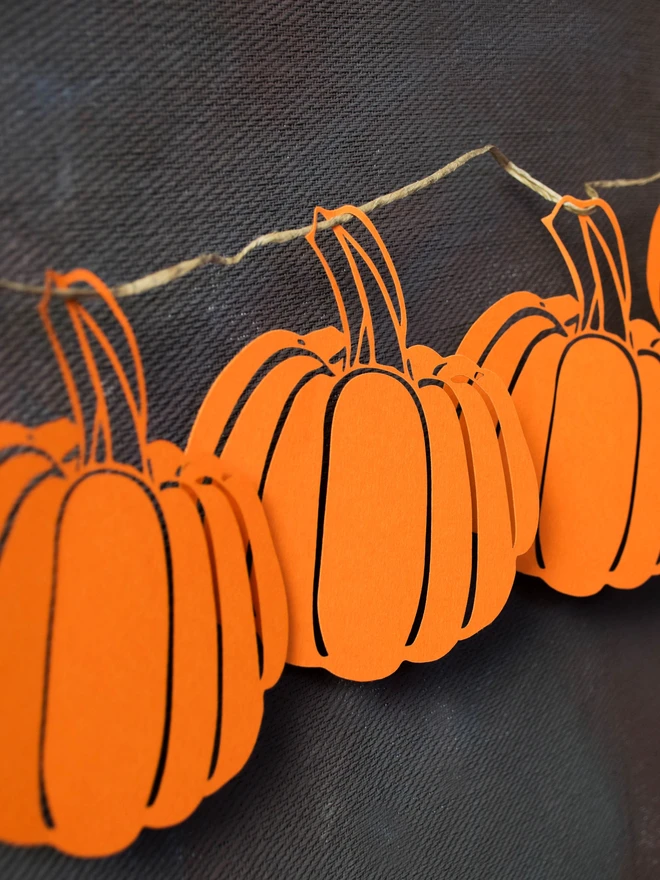 Closeup of orange paper pumpkin decorations displayed against black wall