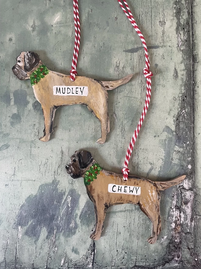 Two border terrier Christmas decorations personalised with black lettering on white with the names " Mudley " and " Chewy" 