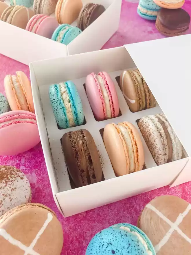 colourful easter macarons in white boxes on a pink background