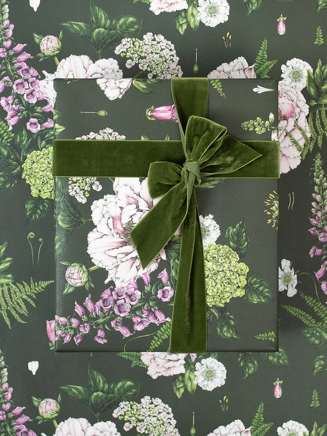 summer garden gift wrap sheet. a box wrapped in dark green illustrated floral gift wrap with a green ribbon.