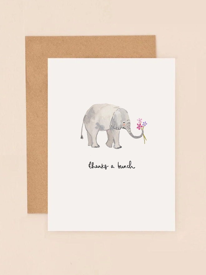A delightful illustration of a cheerful elephant holding a vibrant bouquet of flowers in its trunk, conveying a heartfelt "thank you." The elephant's gentle expression and the colorful blooms add a touch of warmth and appreciation. The design is printed on textured, FSC-certified board, reflecting Louise Mulgrew's commitment to eco-friendly materials.