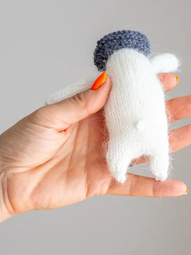 Ottilie The Bear Cashmere Figure , a cashmere bear held by a person against a grey backdrop. 