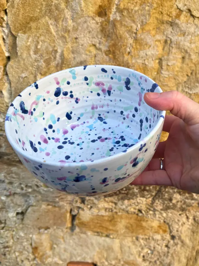 Sweetpea Small Bowl, a person holding a colourful bowl against a brick wall. 