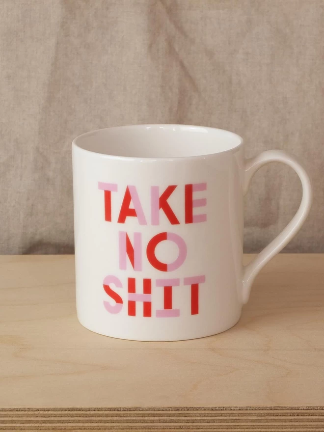 Black & Beech white mug with Do No Harm written on one side and Take No Shit on the other in Pink and Red 