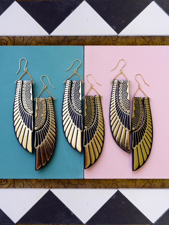 three pairs of gold art deco egyptian scarab wing earrings, on graphic tiles
