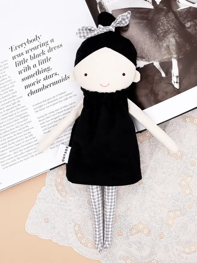 marrie top knot girl doll. a linen doll with a black dress and hair tied up with a grey bow.