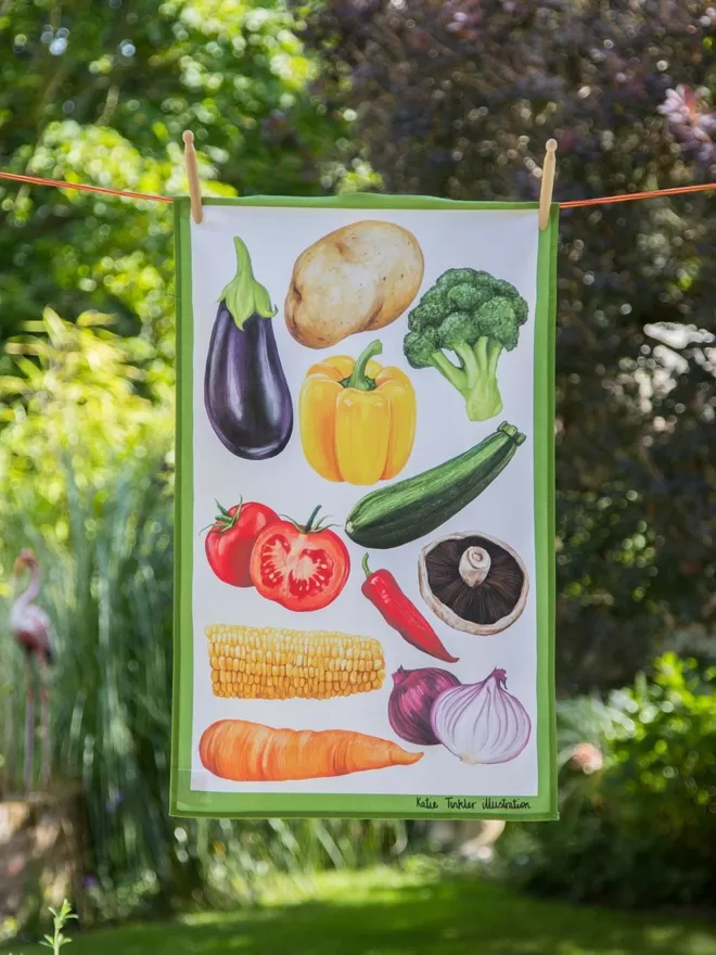 Vegetable Themed Tea Towel by Katie Tinkler seen on a washing line outside.