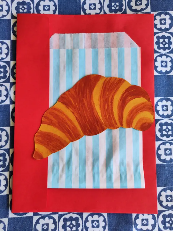 paper croissant painting with striped paper sleeve and red envelope