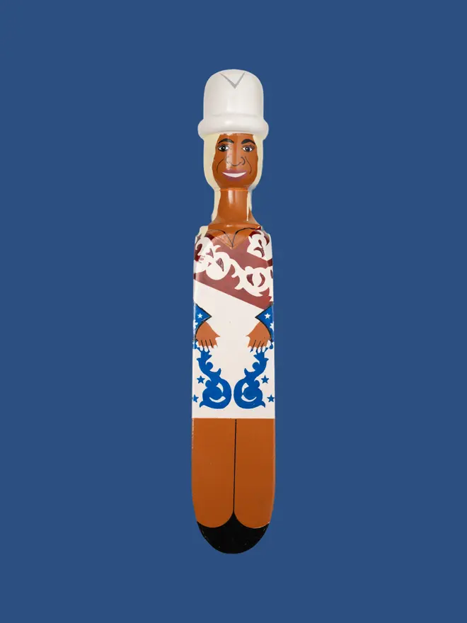 Wooden Door Stopper (Queen B Stars Outfit), a colourful wooden door stop sitting on a plain blue surface