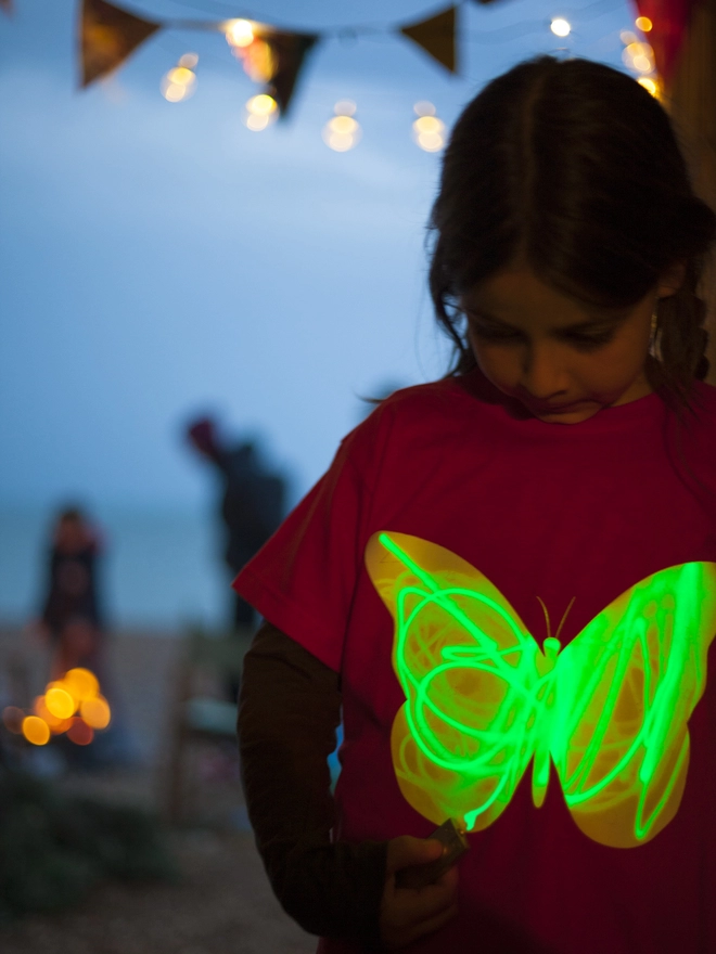 Girl drawing with light onto glow in the dark butterfly tshirt