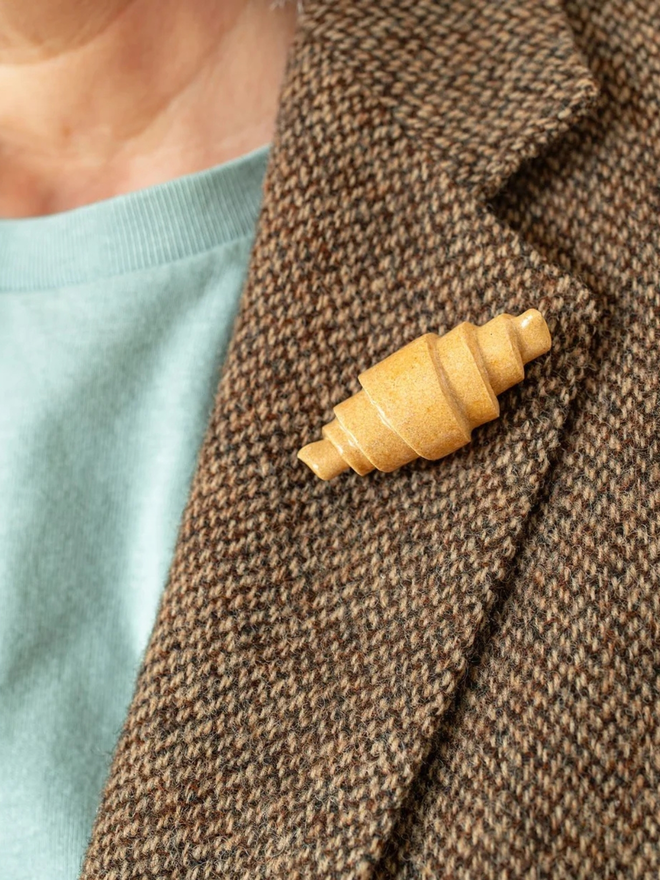 ceramic pastry pin badges. a ceramic croissant badge on a coat lapel.