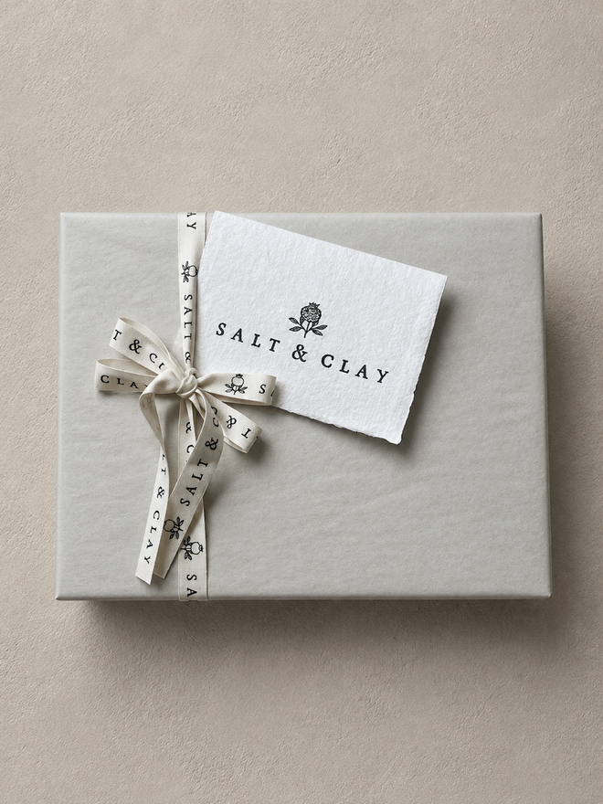 a gift box wrapped in tissue paper with ribbon and a card