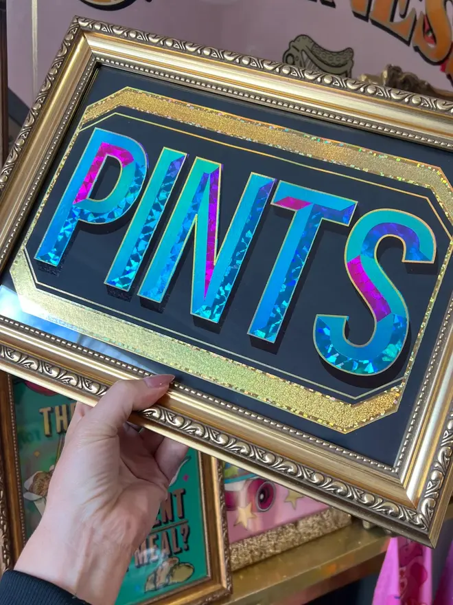 'Pints' ScreenPrint, a colourful screenprint that says 'Pints' held by a person, it sits on a black blackdrop