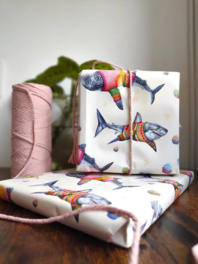 illustrated sharks in jumpers wrapping paper sheet. a sheet of cream wrapping paper featuring illustrated sharks in wooly jumpers.