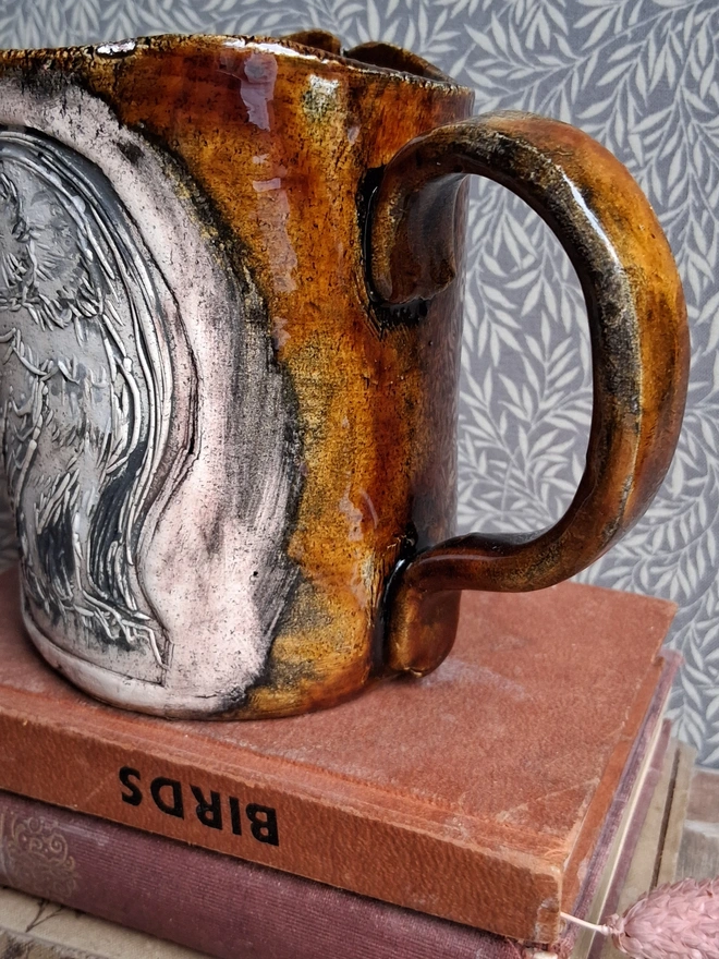 linocut owl ceramic mug.  a brown mug bearing an owl design photographed from the side.