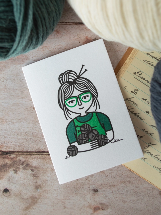 A bold bold illustration of a character enjoying a knitting and crochet hobby surrounded by walls of wool.