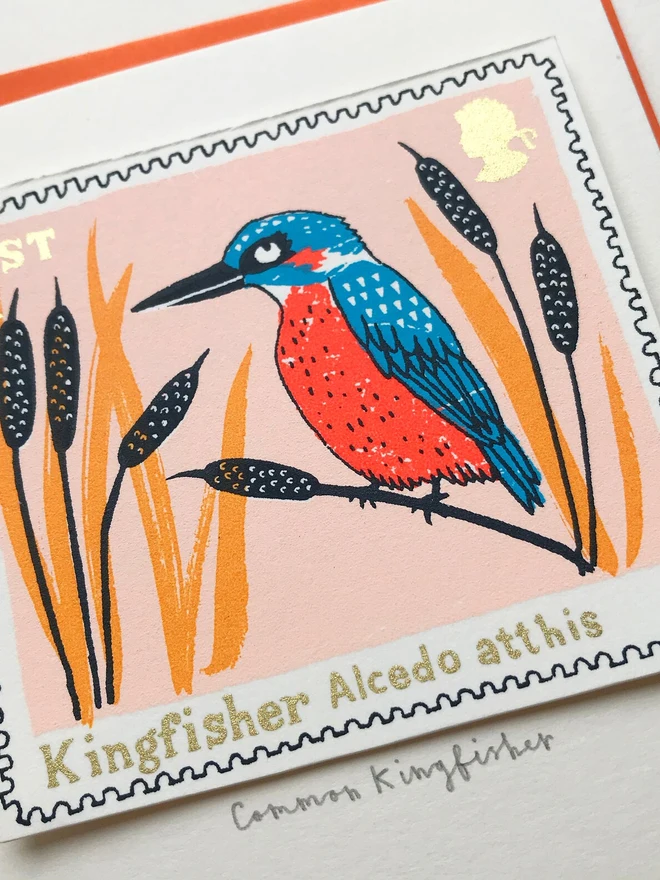 Bird Stamp Card British/ Common Kingfisher Stamp, a white card with a common kingfisher stamp in the centre against an orange envelope on a white background. 