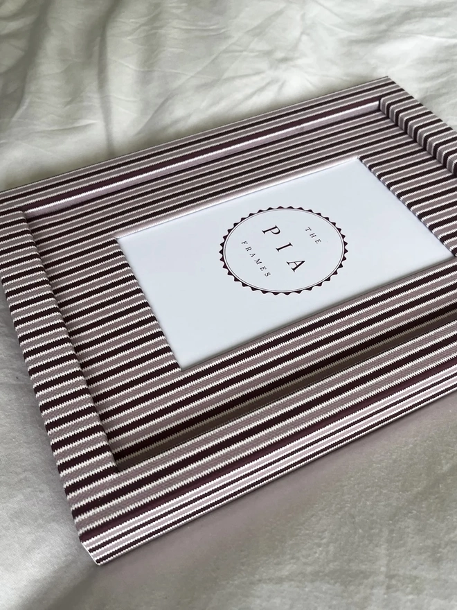 Blush & Burgundy Zigzag Frame, a colourful striped frame sitting on a plain white surface. 