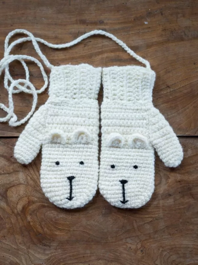 EKA Animal Mittens in white seen on a wooden floor.