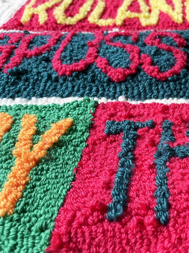 punch needle wool type in bright coloured wool on contrasting square background