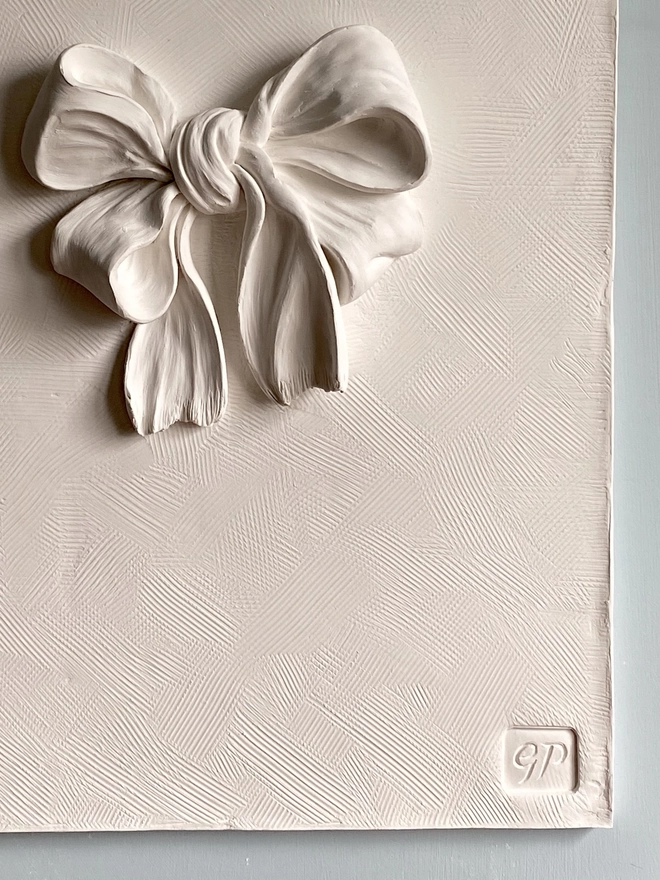 Detail of plaster of paris bas-relief wall plaque with bow and ribbon
