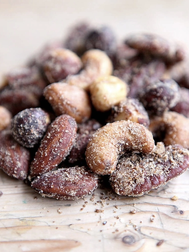 Spiced Smoked Nuts Packet, a group of nuts sitting on a wooden surface. 