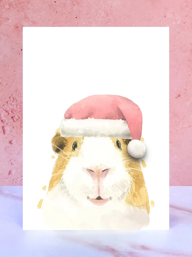 A Christmas card featuring a hand painted design of a guinea pig, stood upright on a marble surface. 