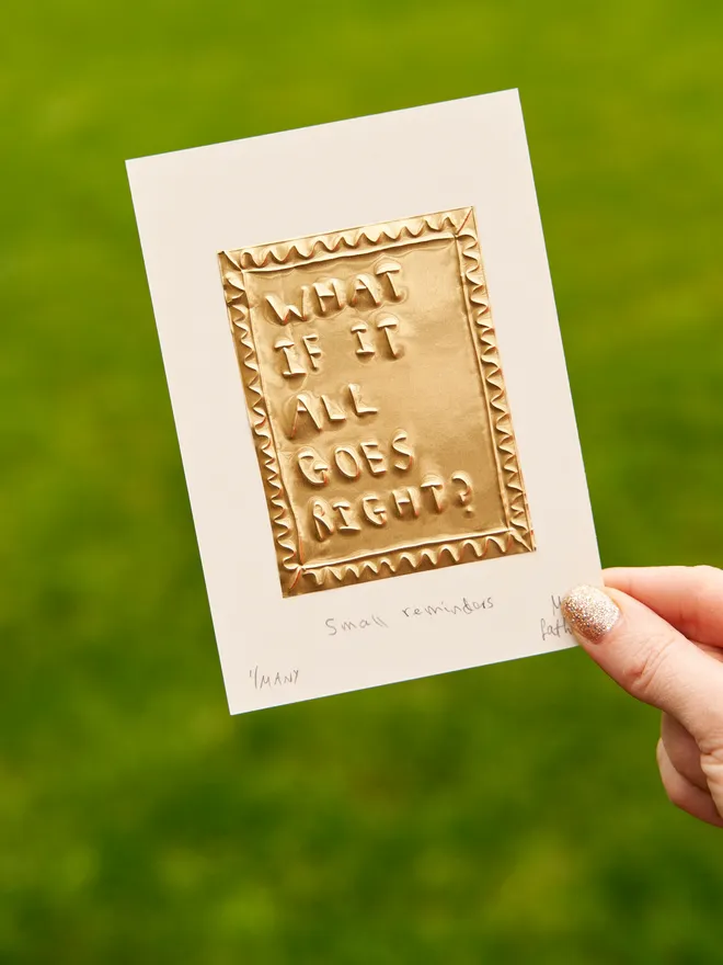 What if it all goes right - tin embossing on white card, in front of a grass background, held by a female hand