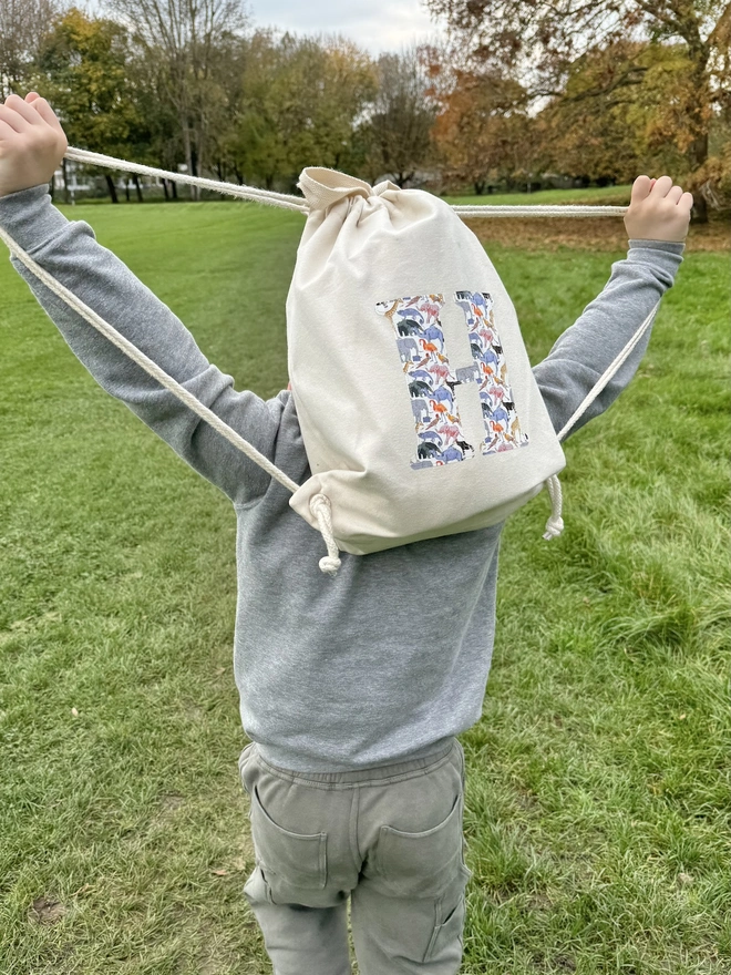 a 5 year old boy wearing a Magnificent Stanley Personalised Liberty Print Drawstring Backpack with his initial on in queue for the zoo animal print